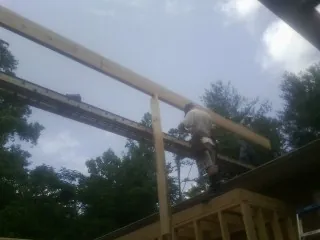 Carpenter setting a ridge beam over a new addition frame — Ice Dam Removal by Roofing Brothers in Point Clear