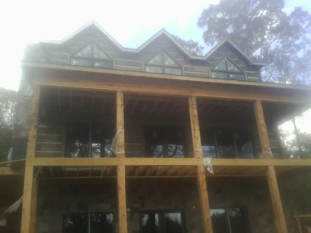 Dormers and porch framing on a large log home under construction — Roof Coating work by our crew in Point Clear