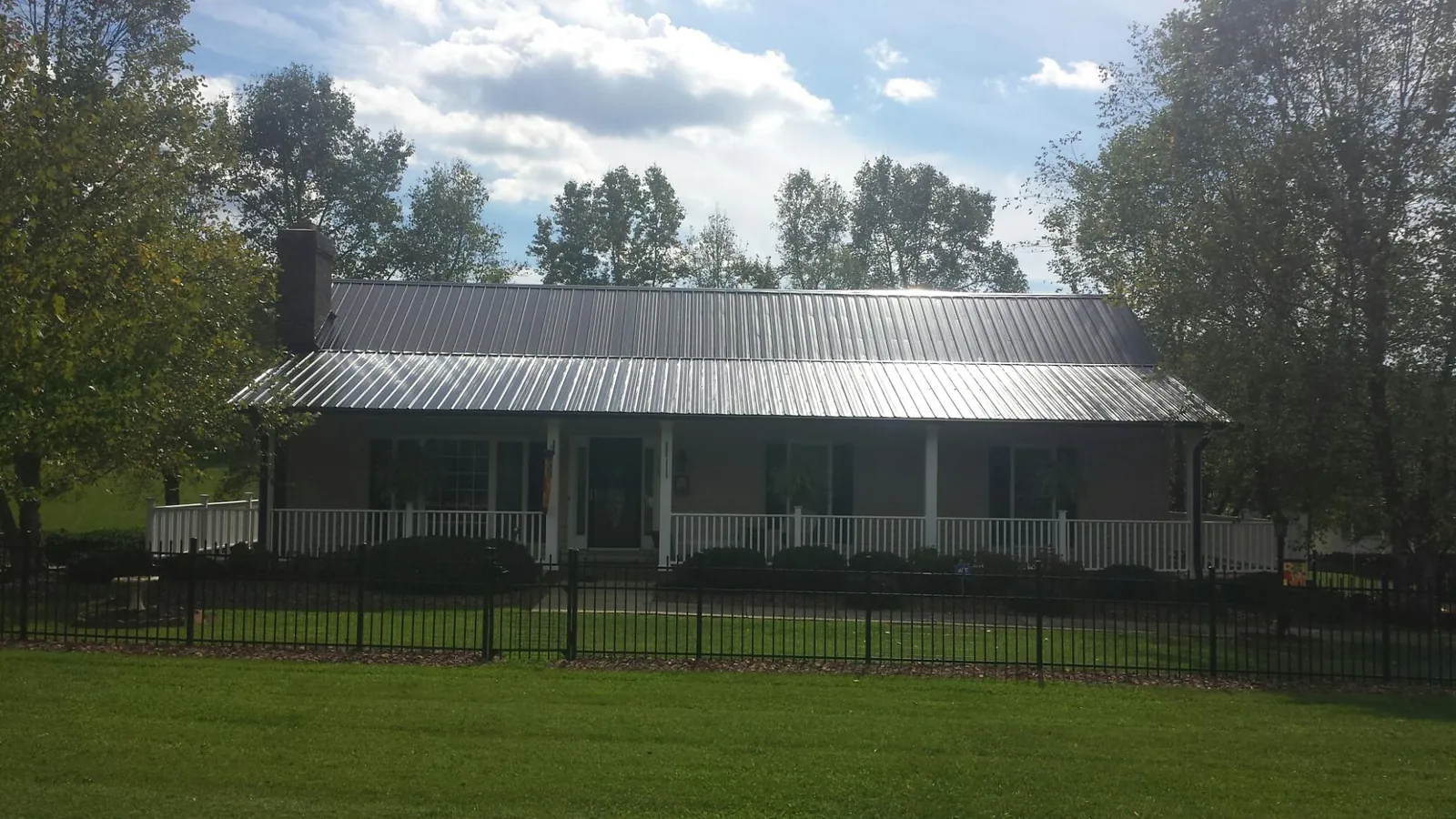 Gray metal roof on a brick ranch with a full width front porch — Gutter Guard Installation work by our crew in Point Clear