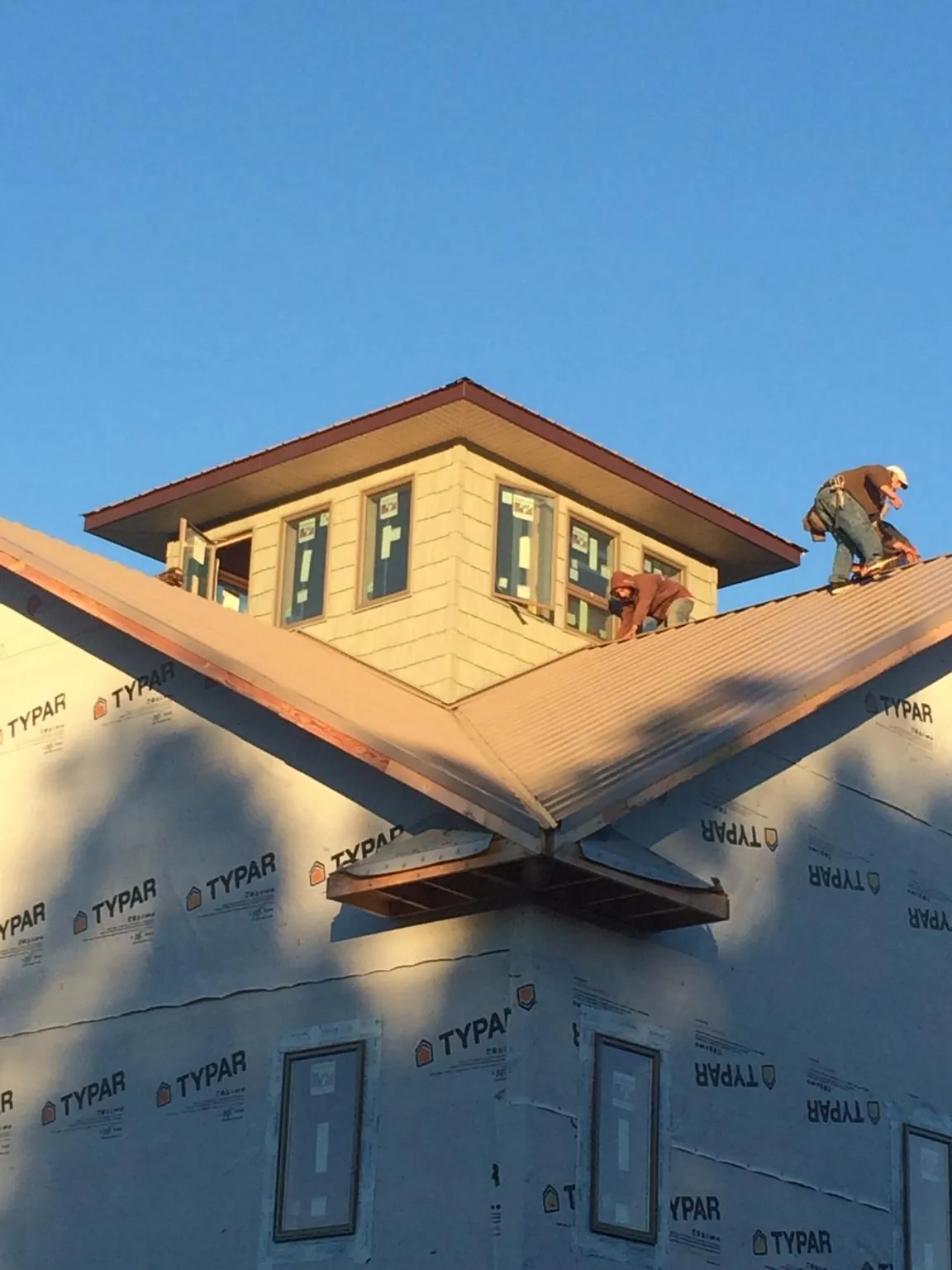 Roofers working around a rooftop cupola on a new metal roof at sunset — Roof Waterproofing in Point Clear by Roofing Brothers